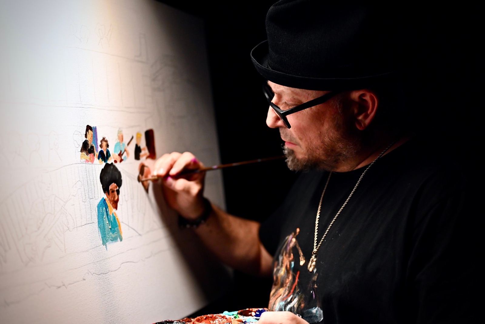 Frenchy, palette in hand, adding color to the first figures of a new live painting